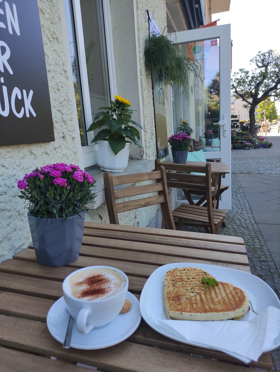 Panini und Cappuccino auf einem Holztisch vor der Kaffee Station