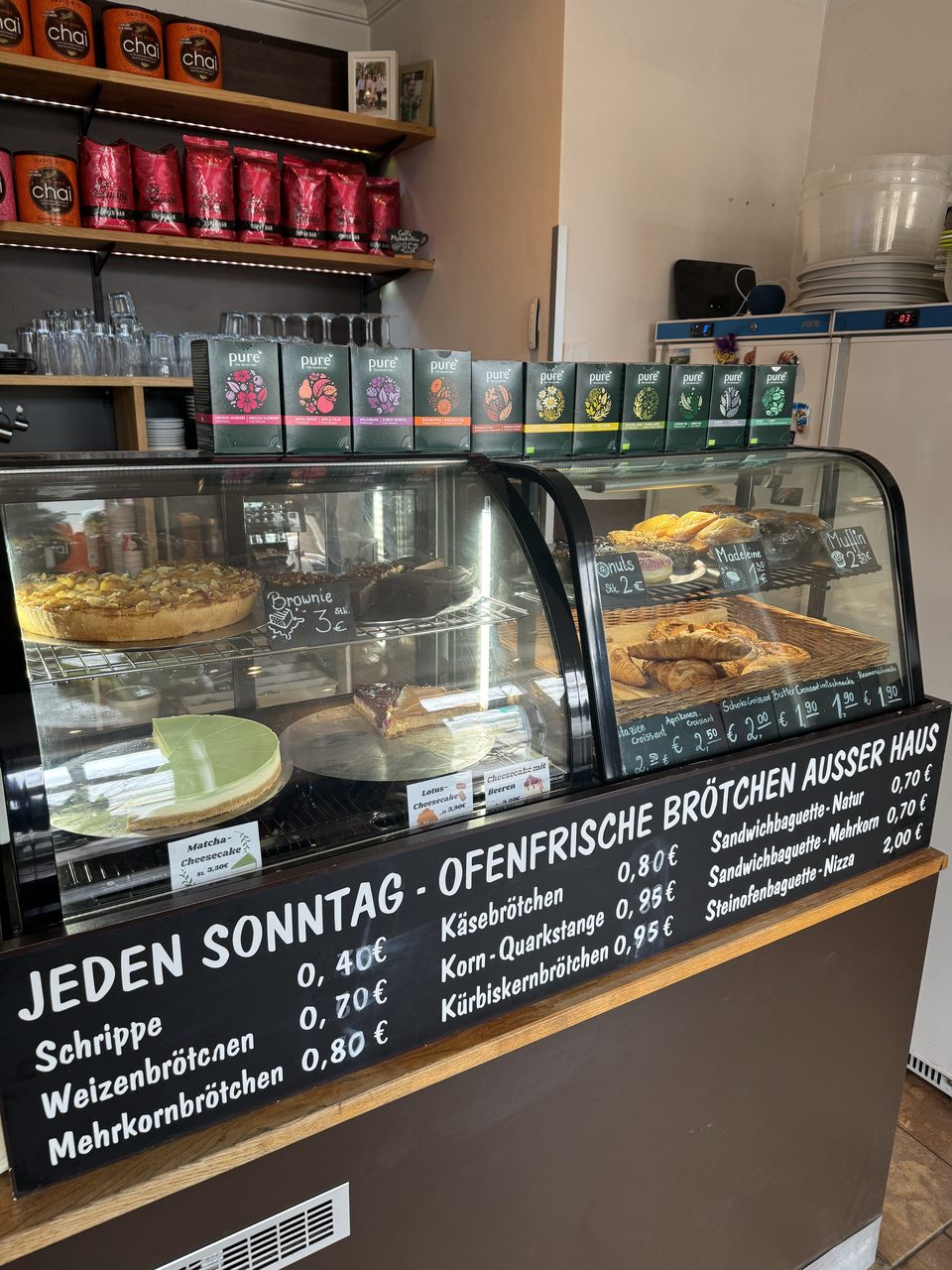 Blick in die Vitrine mit hausgemachten Cheesecakes und Brötchenpreisen